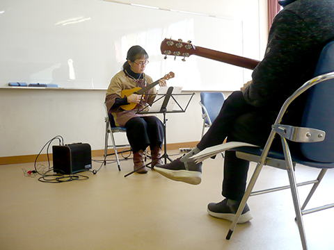 ウクレレを弾く生徒さん（50代女性）と演奏を聴く生徒さんたちの様子