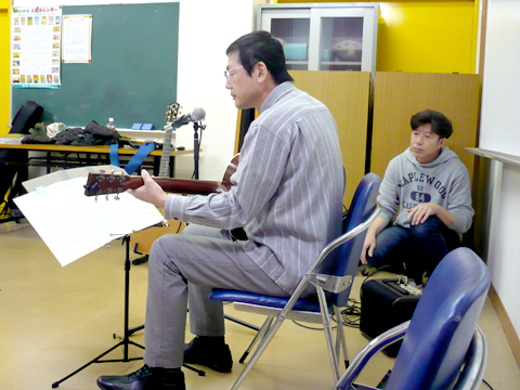 50代男性の生徒さんのギターの弾き語りの様子を横側から