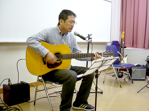 一人でギターの弾き語りをする生徒さん（50代男性）の写真