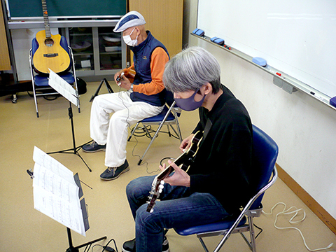 ウクレレを弾く生徒さん（70代男性）とギターを弾く講師の写真