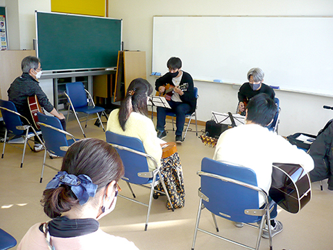 生徒さん（40代男性）と講師のギター演奏を聴く生徒さんたちの様子