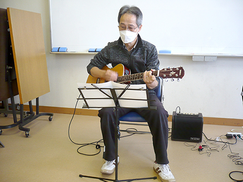 アコースティックギターを弾く生徒さん（60代男性）の写真